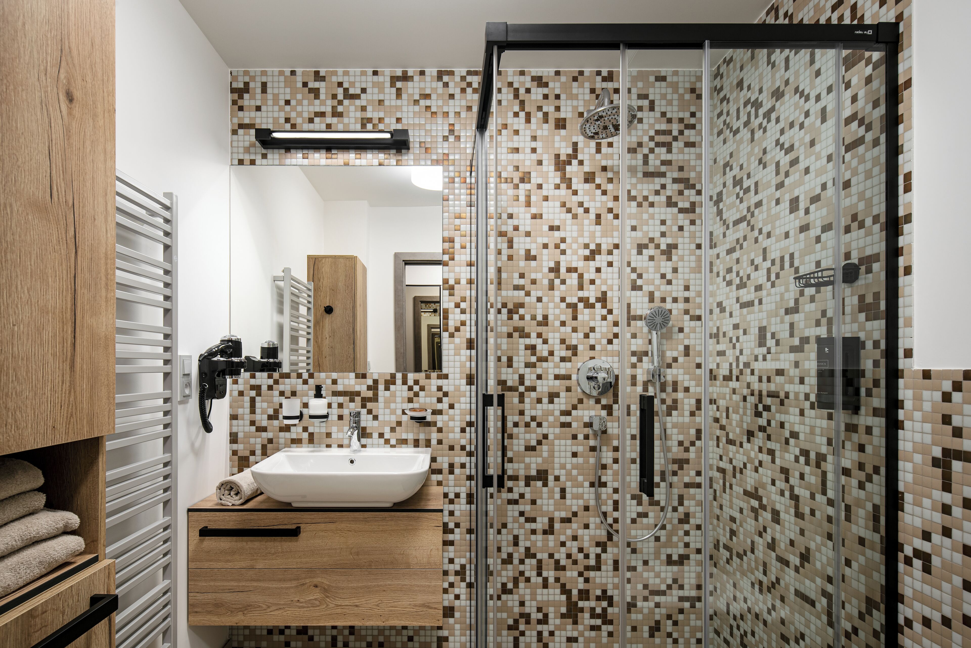 A modern bathroom with a glass-enclosed shower, a wooden vanity, and a tiled backsplash.