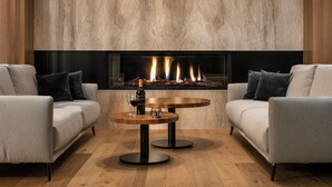 Un salon moderne avec deux canapés, une table ronde en bois et une cheminée dont on peut voir les flammes.