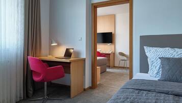 Una habitación de hotel con cama, escritorio, silla, televisor y armario.