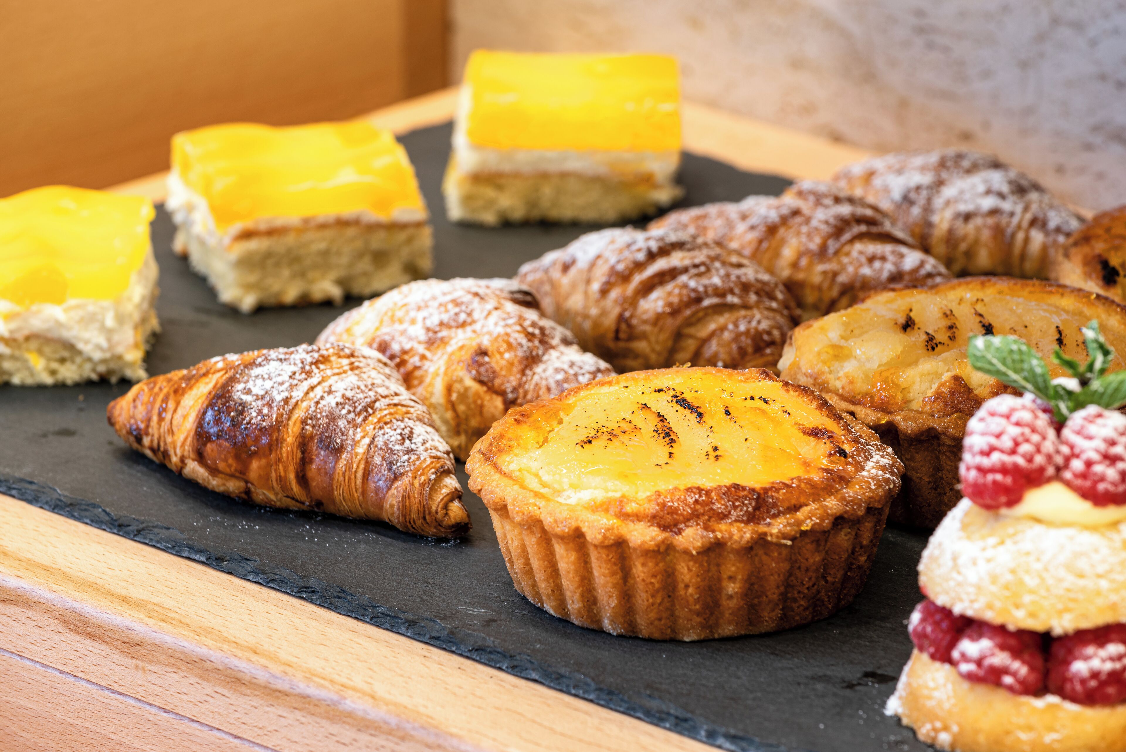 A variety of pastries and desserts on a slate serving board.