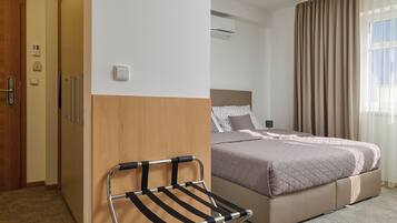Ein Hotelzimmer mit Bett, Stuhl, Holzschrank und Tür.