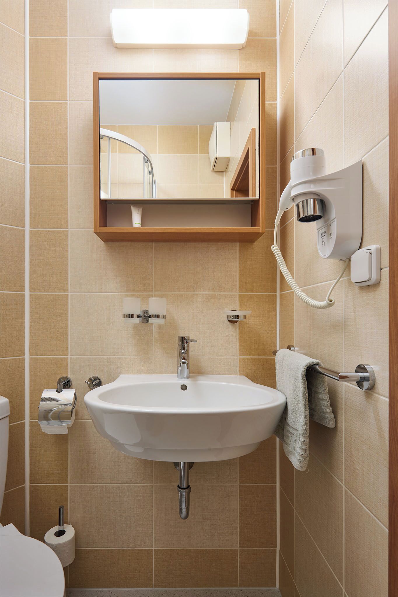 Un baño con lavabo, espejo, toallero y secador de pelo.