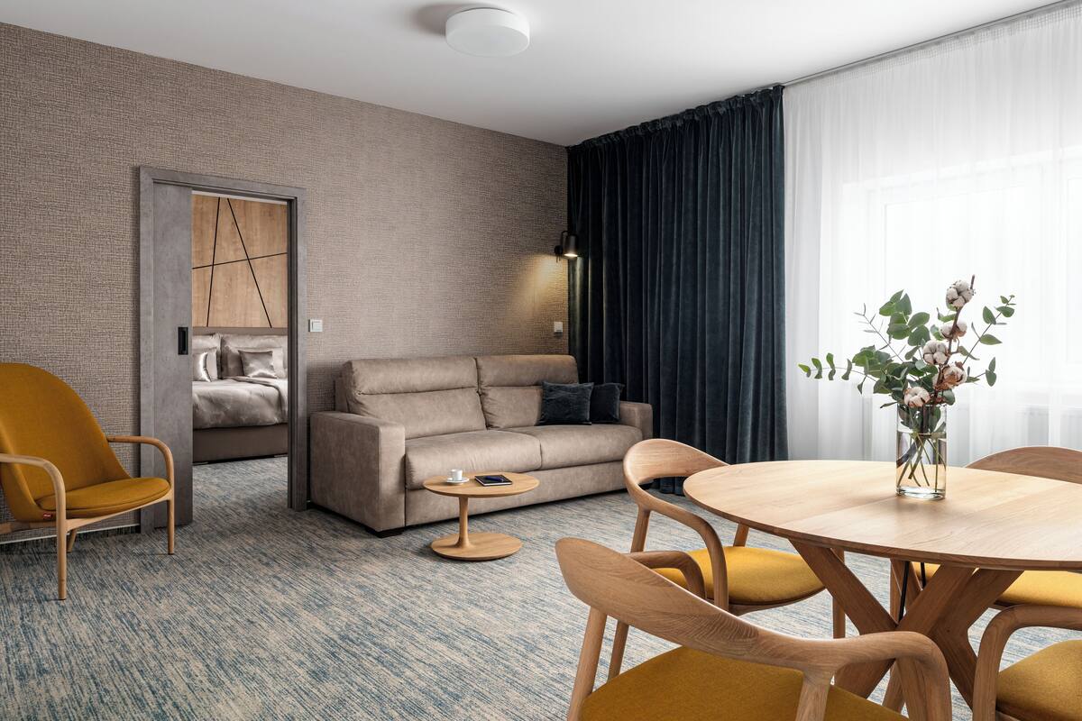 Une chambre d’hôtel moderne équipée d’un canapé, de fauteuils, d’une table à manger et d’une petite table d’appoint.