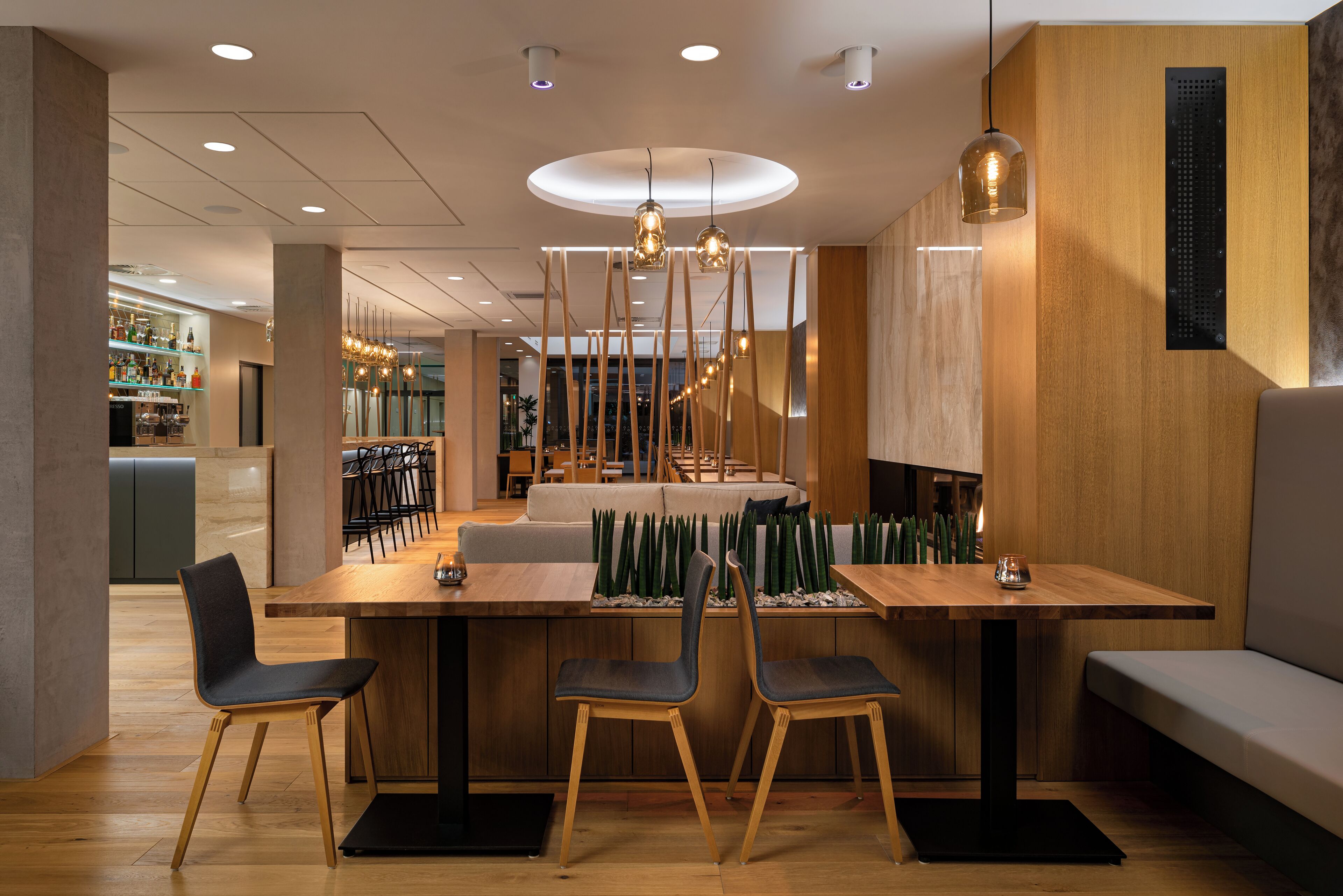 A modern dining area with a wooden table, two chairs, and a central island with plants.
