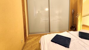 Een slaapkamer met een schuifdeurkast, een bed met witte beddengoed en een houten vloer.