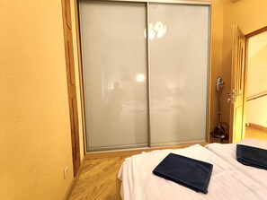 A bedroom with a sliding door closet, a bed with white bedding, and a wooden floor. - Swedish Gate One Bedroom Apartments Old Town Riga (Riga)