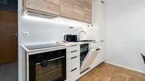 Eine moderne Küche mit weißen Schränken, einem Backofen, einer Spülmaschine und einer Kaffeemaschine.
