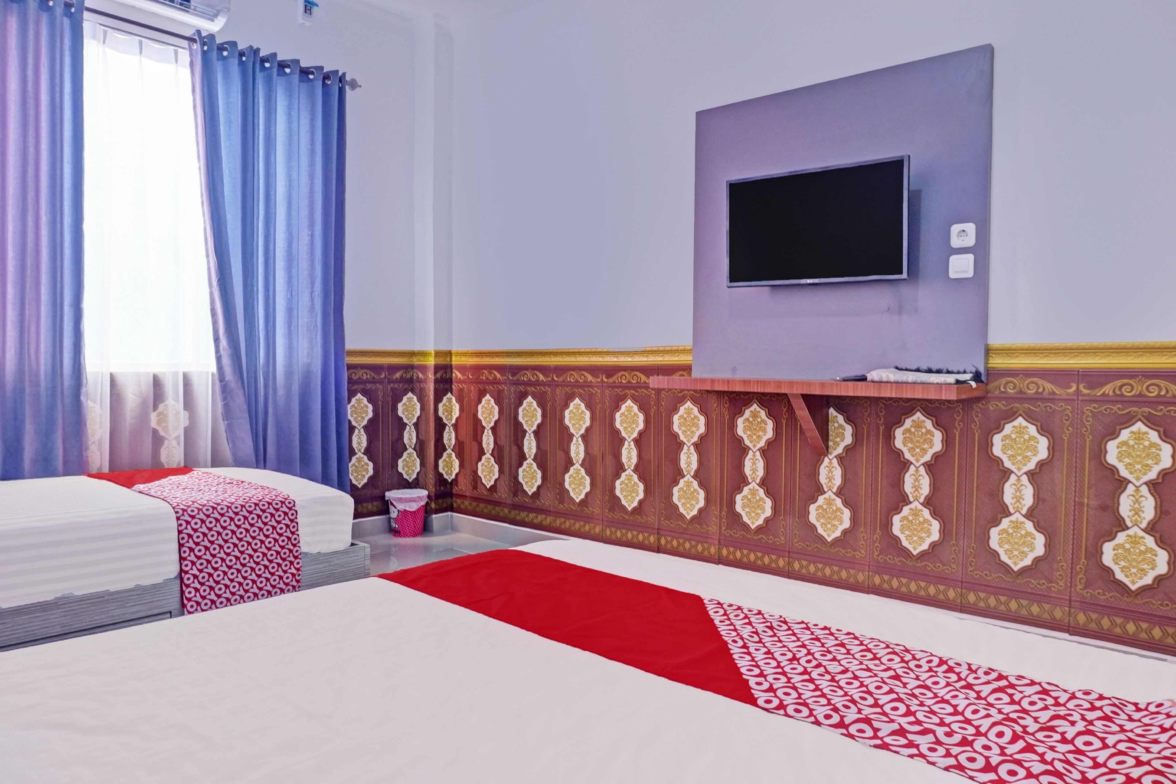 Quarto de hotel com uma cama, televisão na parede e design de parede estampado.
