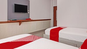A hotel room with two beds, a flat-screen TV mounted on the wall, and a wooden headboard.
