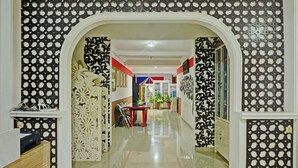 A hallway with a decorative archway, a red table, and patterned walls.