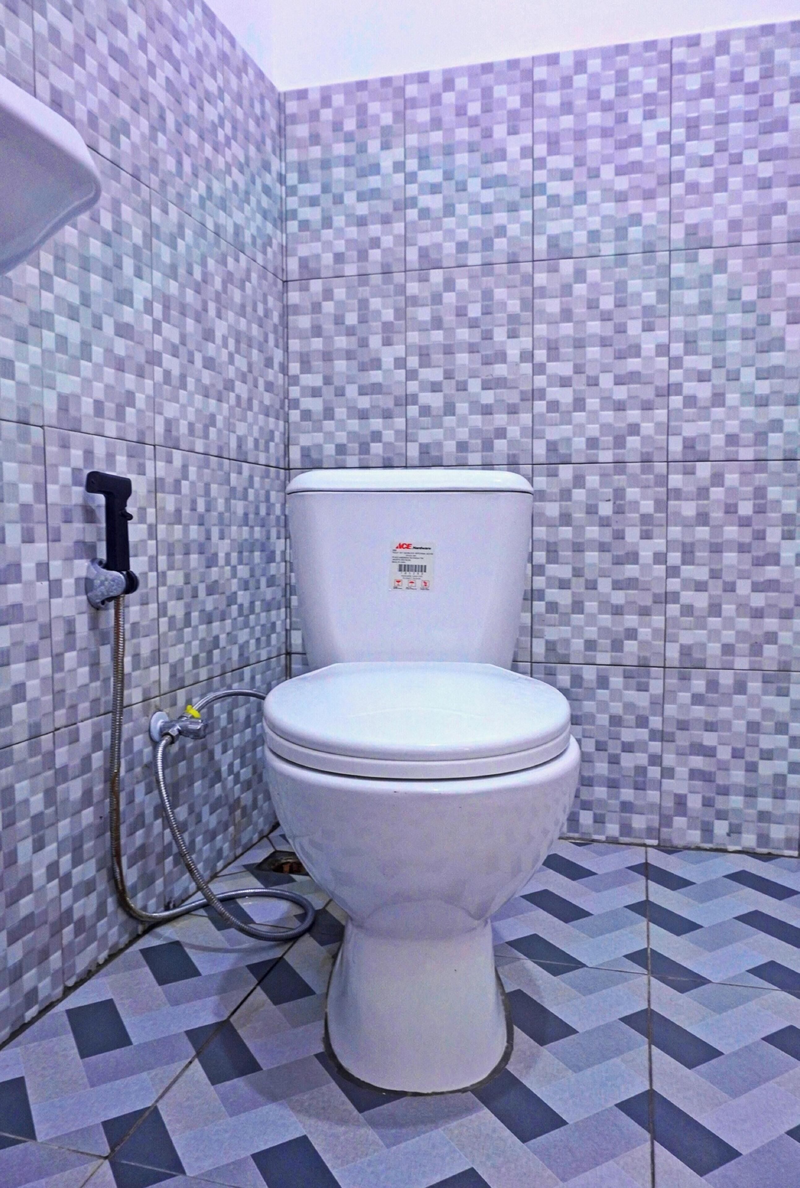 Un baño con inodoro, ducha y paredes y suelo de baldosas.
