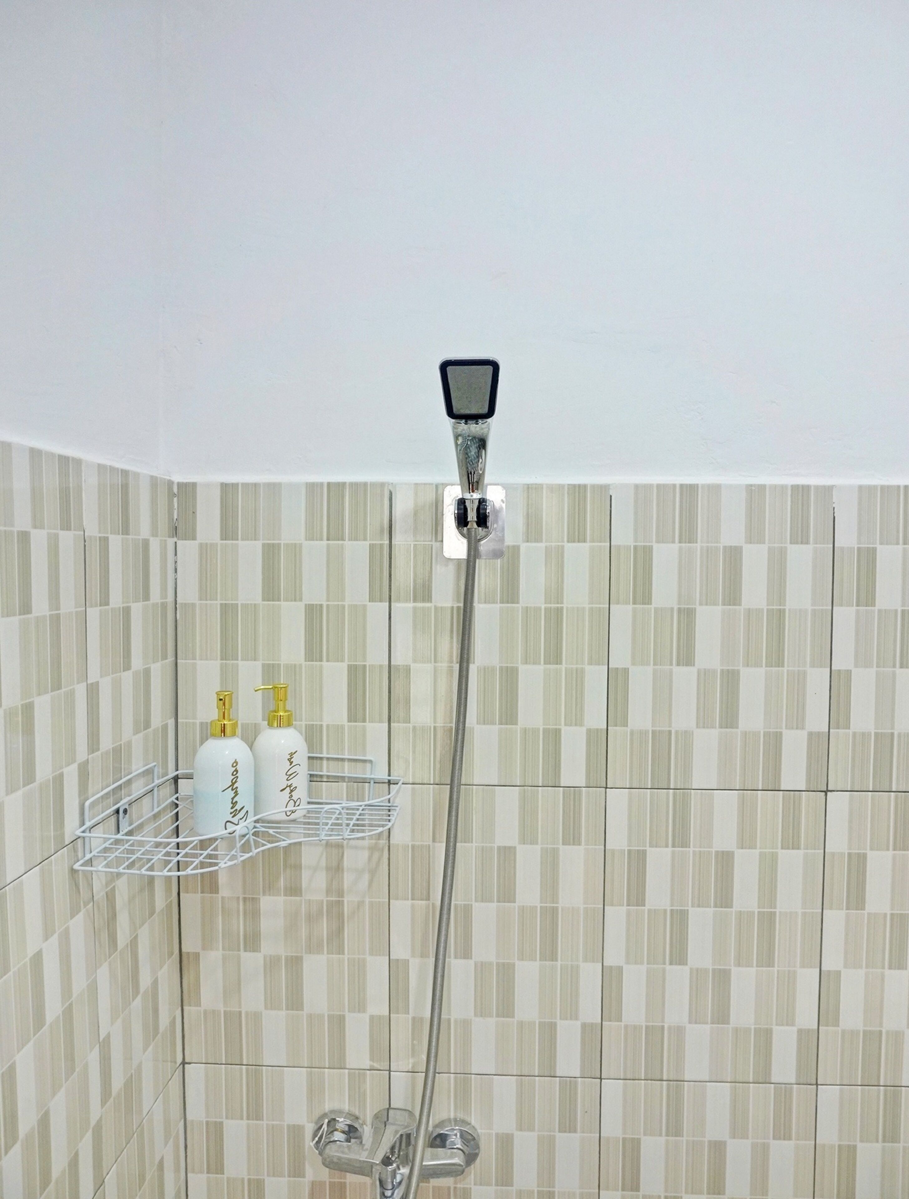 A bathroom with a shower, tiled walls, and a shelf with toiletries.