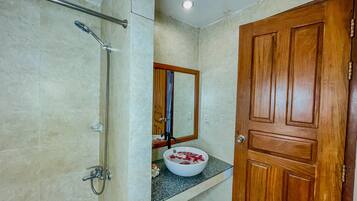 Un baño con ducha, lavabo y puerta de madera.