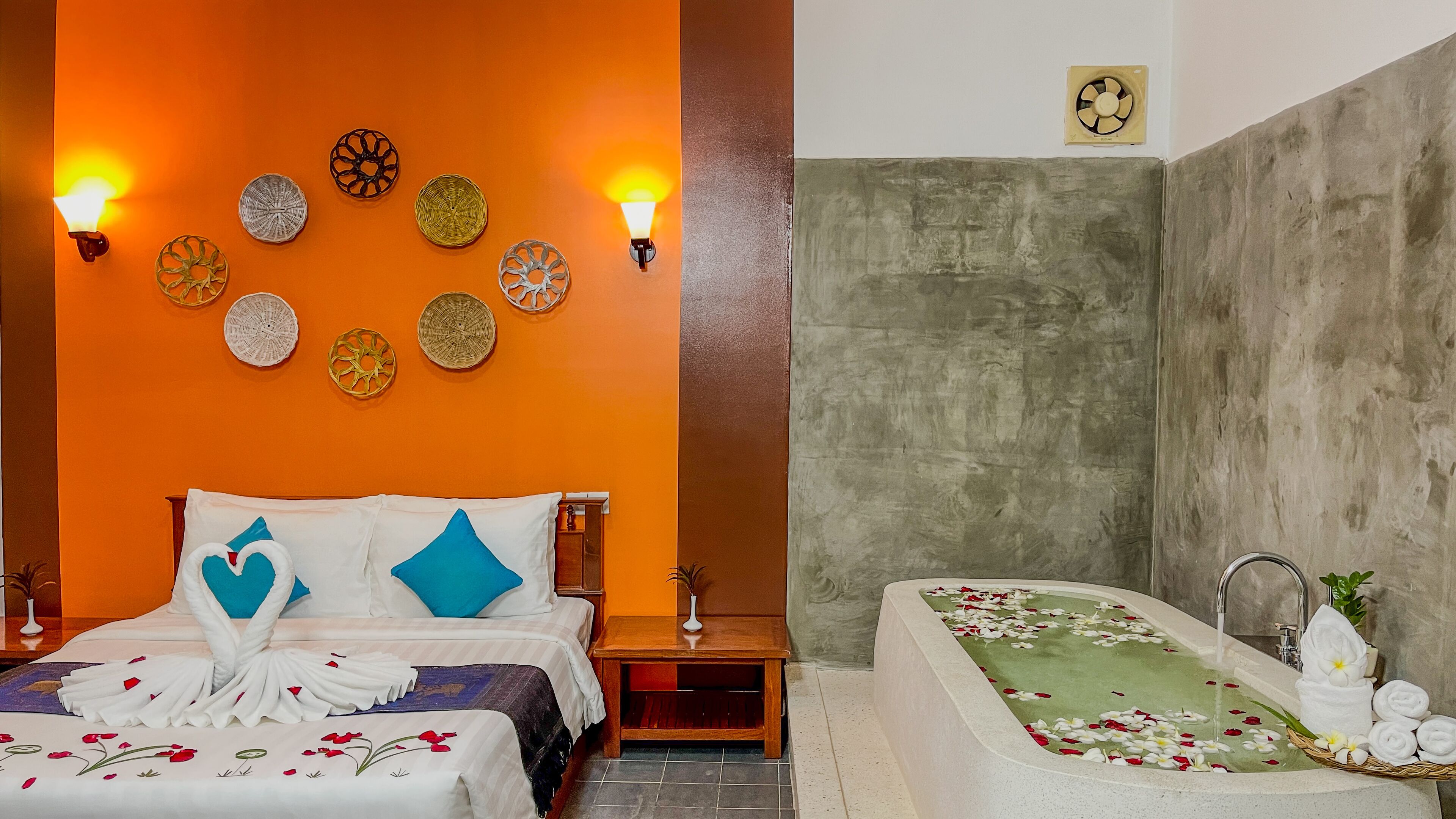 A hotel room with a bed, a nightstand, a wall-mounted light fixture, and a bathroom with a bathtub.
