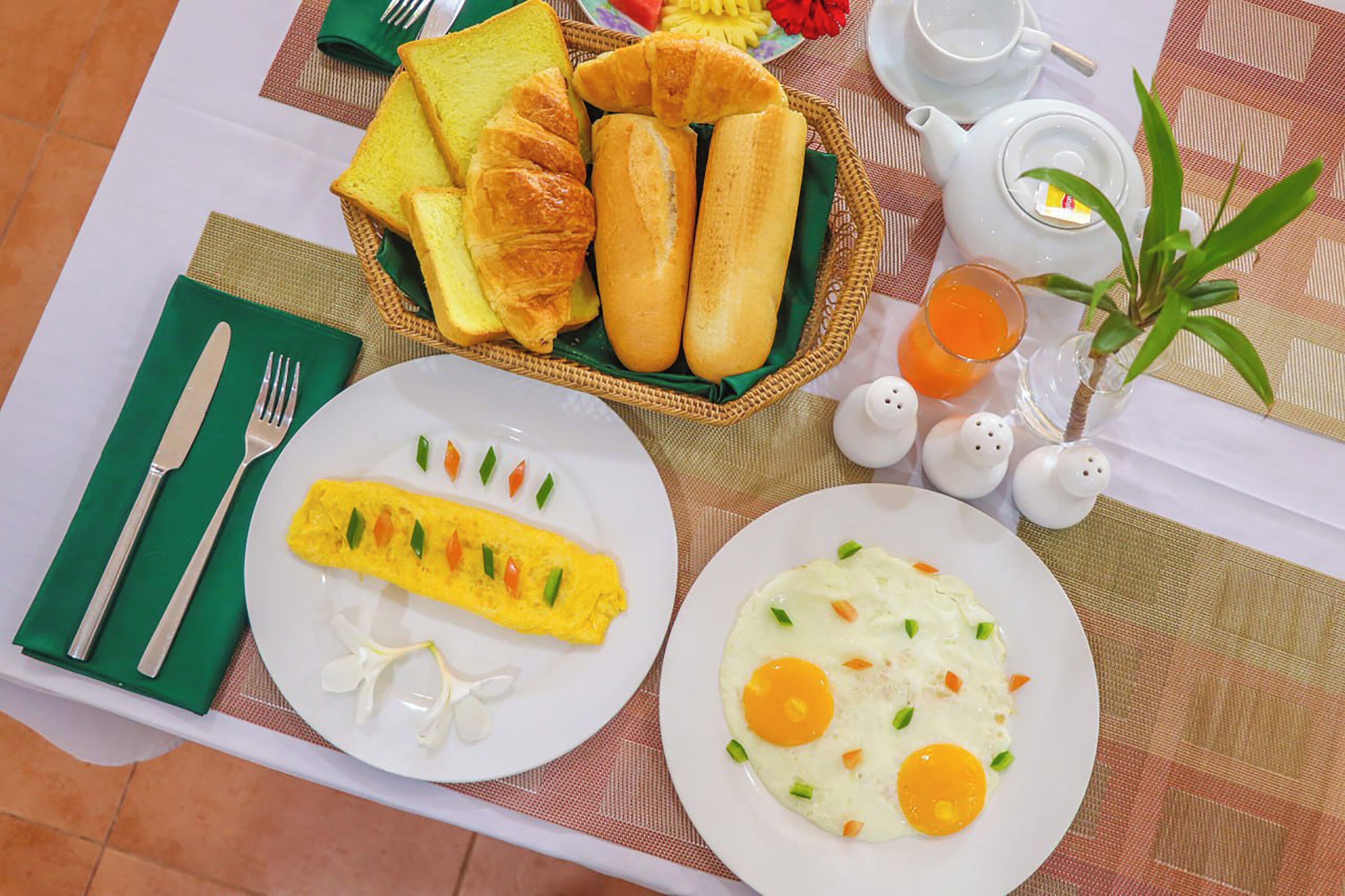 A breakfast setting with croissants, an omelette, and toast on a table with a placemat.