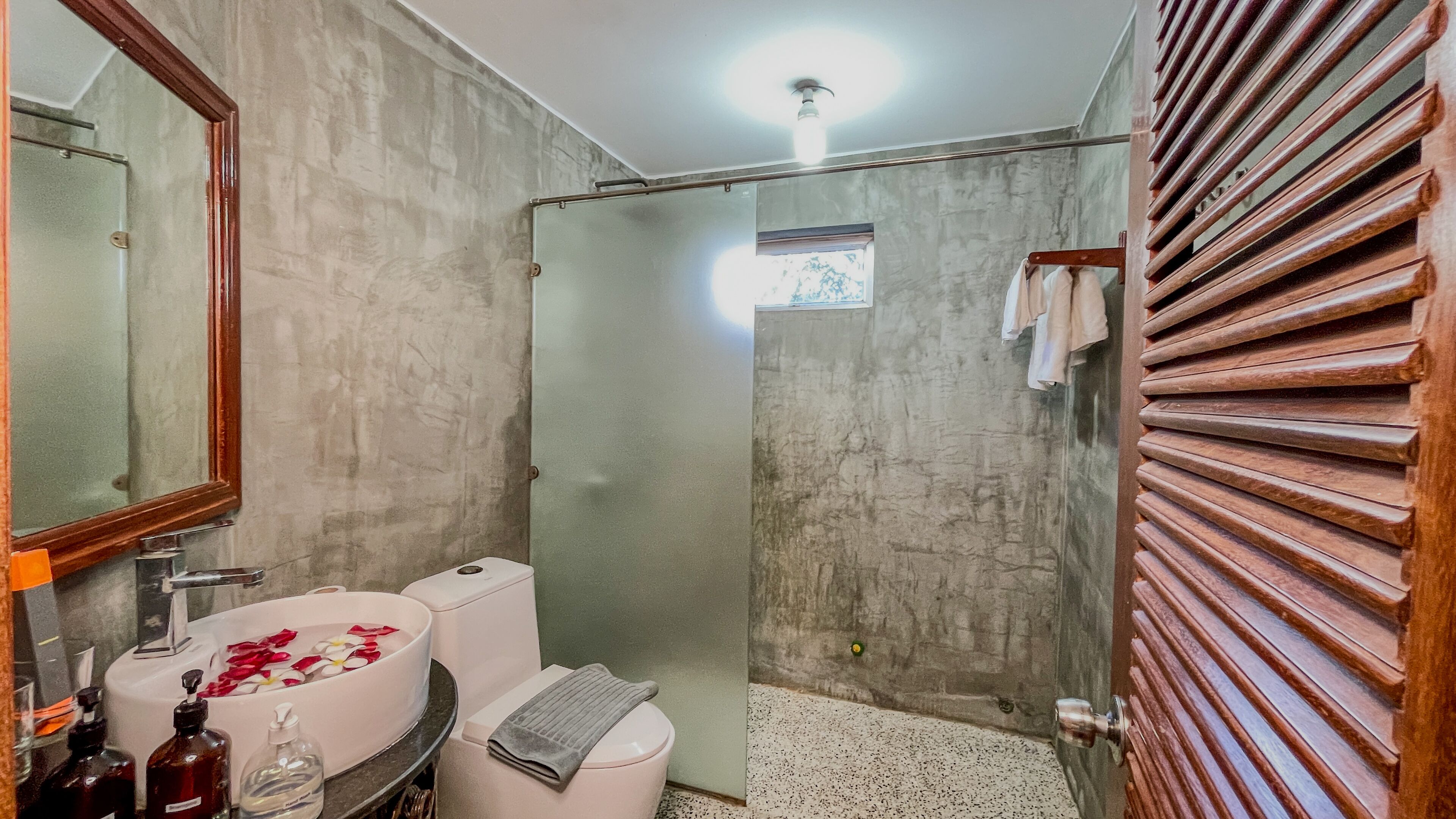 Un baño con ducha, inodoro, lavabo y espejo.