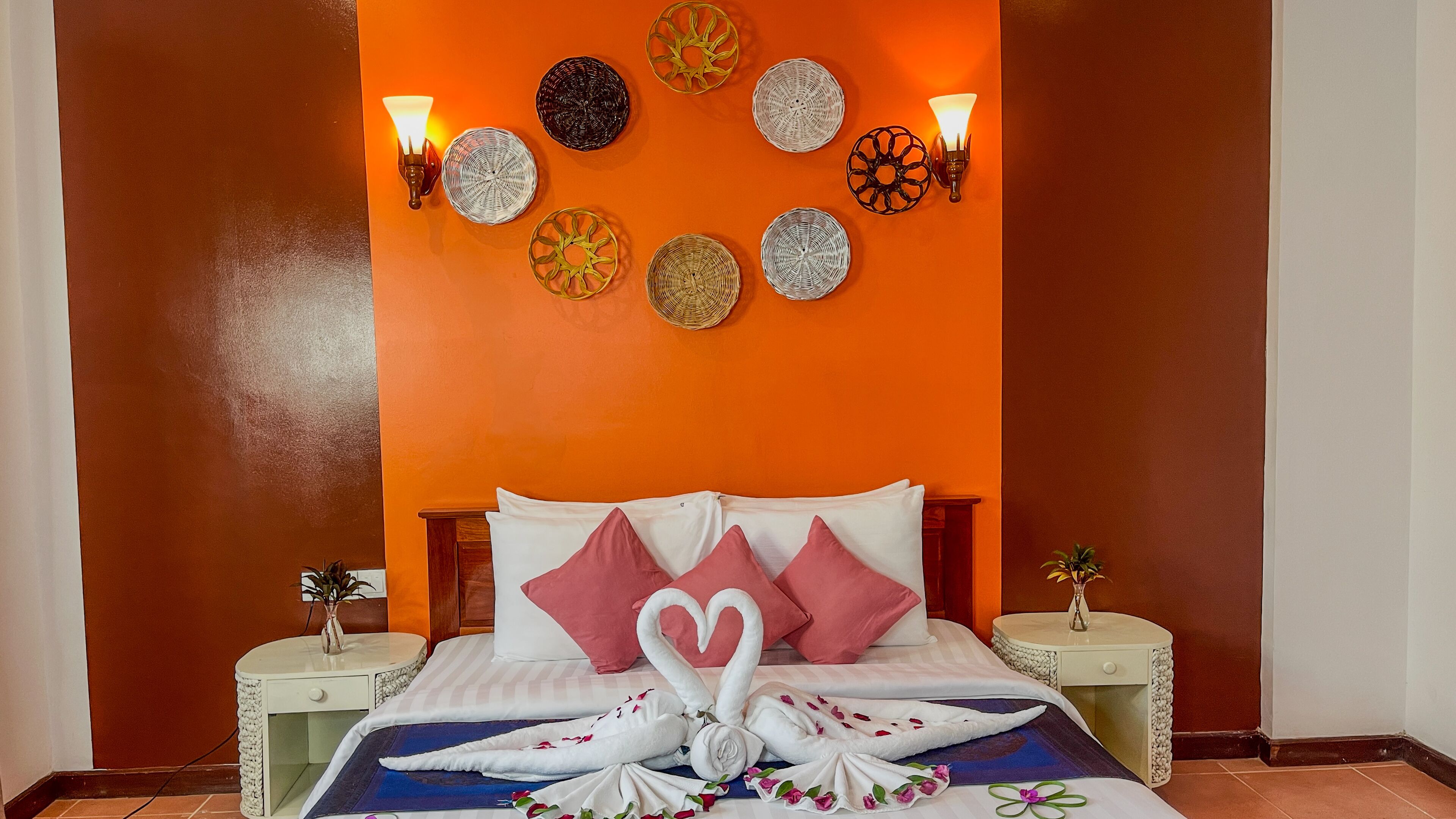 A hotel room with a bed, pillows, a decorative wall, and two nightstands.