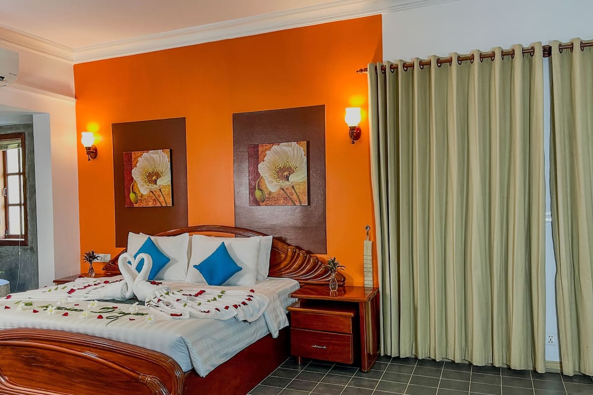 A hotel room with a wooden bed, two wall-mounted lamps, a window with a view, and a curtain.