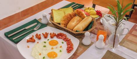 A breakfast table with eggs, toast, croissants, and a fruit plate.