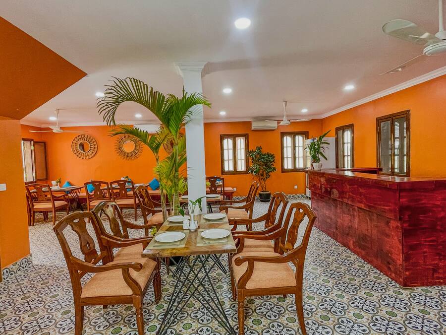 A dining area with a central table surrounded by chairs, a reception desk, and decorative wall mirrors.