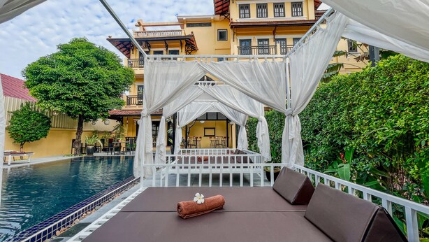 Un área de descanso junto a la piscina, con toldo, asientos y vistas al agua.