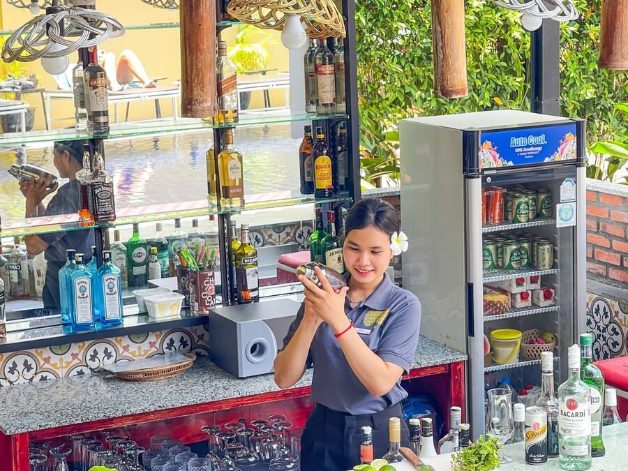 Un espace bar comprenant un assortiment de bouteilles d’alcool, de verres et un réfrigérateur rempli de boissons.