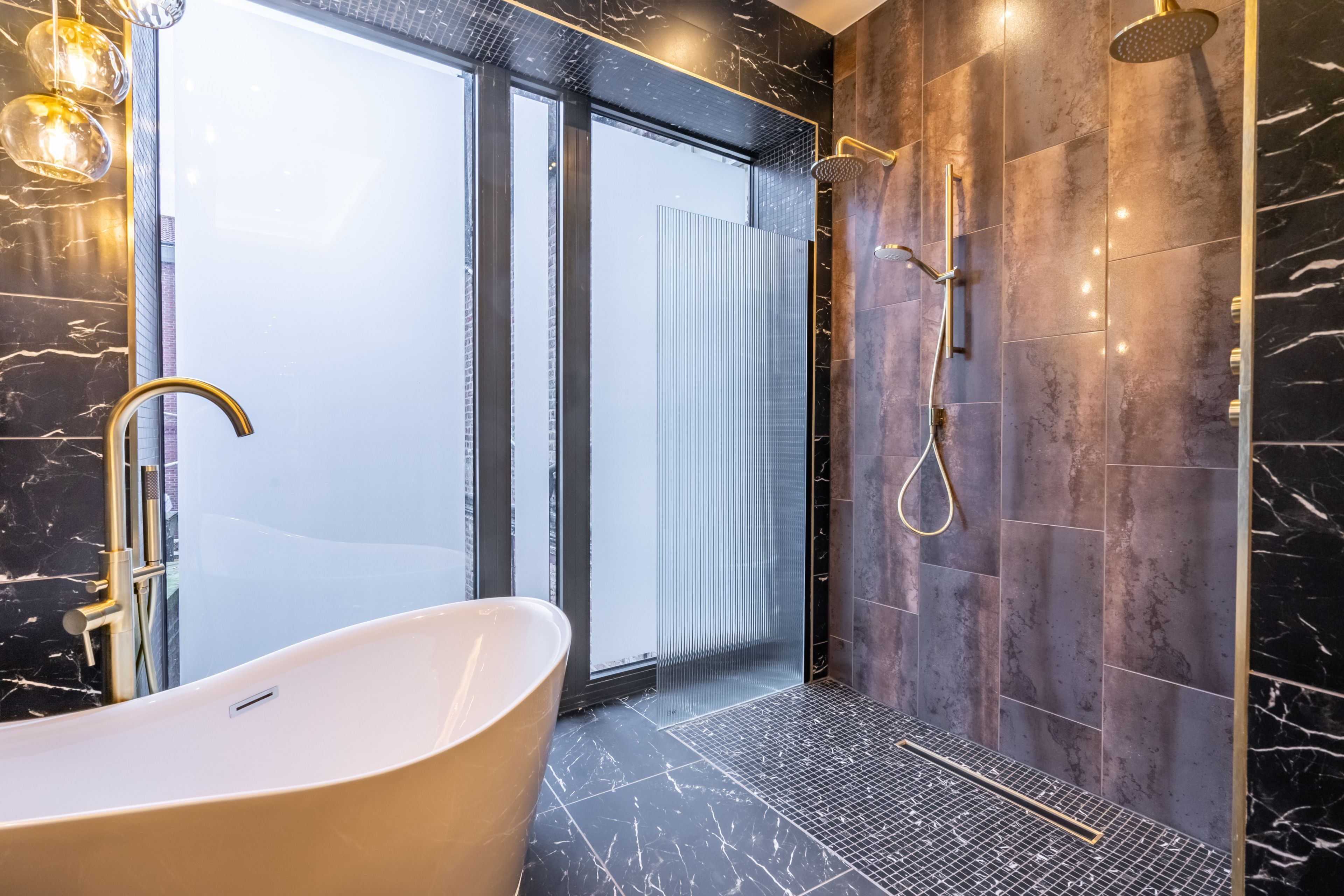 Un baño moderno con una bañera independiente, una ducha a ras de suelo y un ventanal de cristal que da a un balcón.