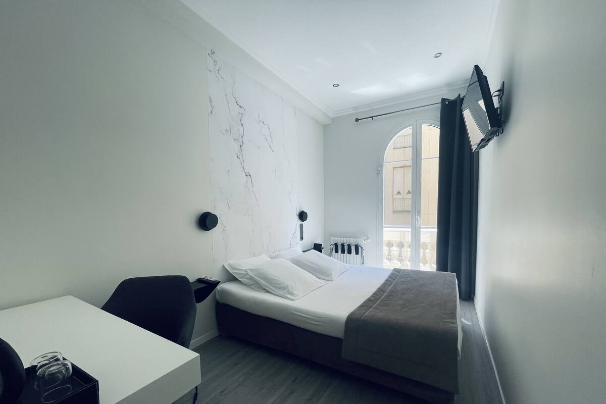Una habitación de hotel moderna con una cama, un escritorio y vistas a la ciudad.