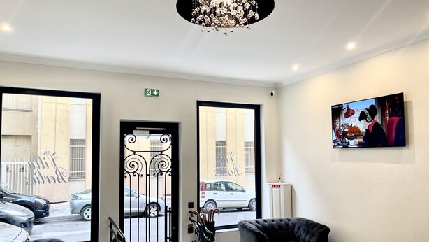 Een moderne hotellobby met een kroonluchter, een zithoek en kunstwerken aan de muur.