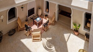 Un intérieur spacieux avec un plafond haut, un espace de détente central doté d’un foyer, et plusieurs balcons avec des garde-corps.
