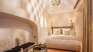 Une chambre à coucher comprenant un lit, un banc, une petite table avec un chandelier et un luminaire au plafond original.