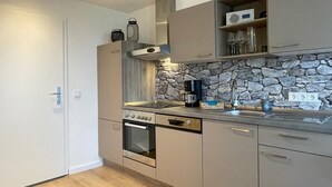 A modern kitchen with a stone backsplash, built-in oven, and a coffee maker. - Apartment Tälerblick Maxi - with large balcony and great view (Böbrach)