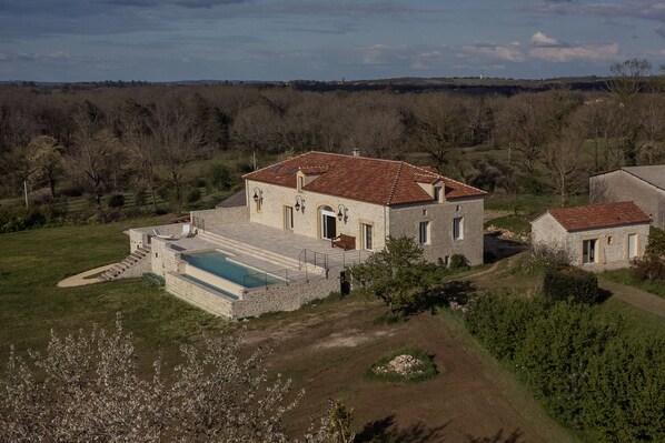 A stone house with a swimming pool, surrounded by a garden and a forested landscape. - Aux Truffes de Combecave (Mauroux)