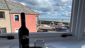 A bottle of wine on a tray with four glasses on a windowsill.