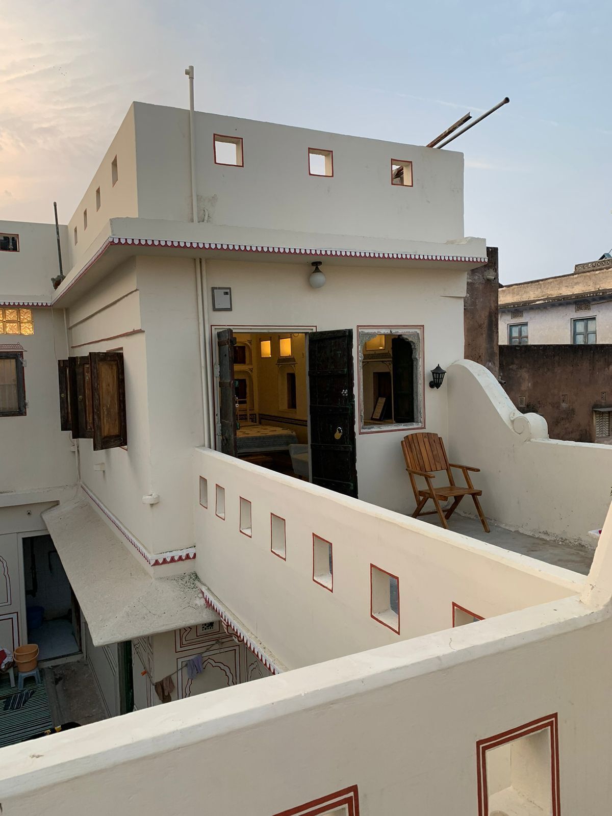 A multi-story building with a balcony, a chair, and a door leading to an interior space.