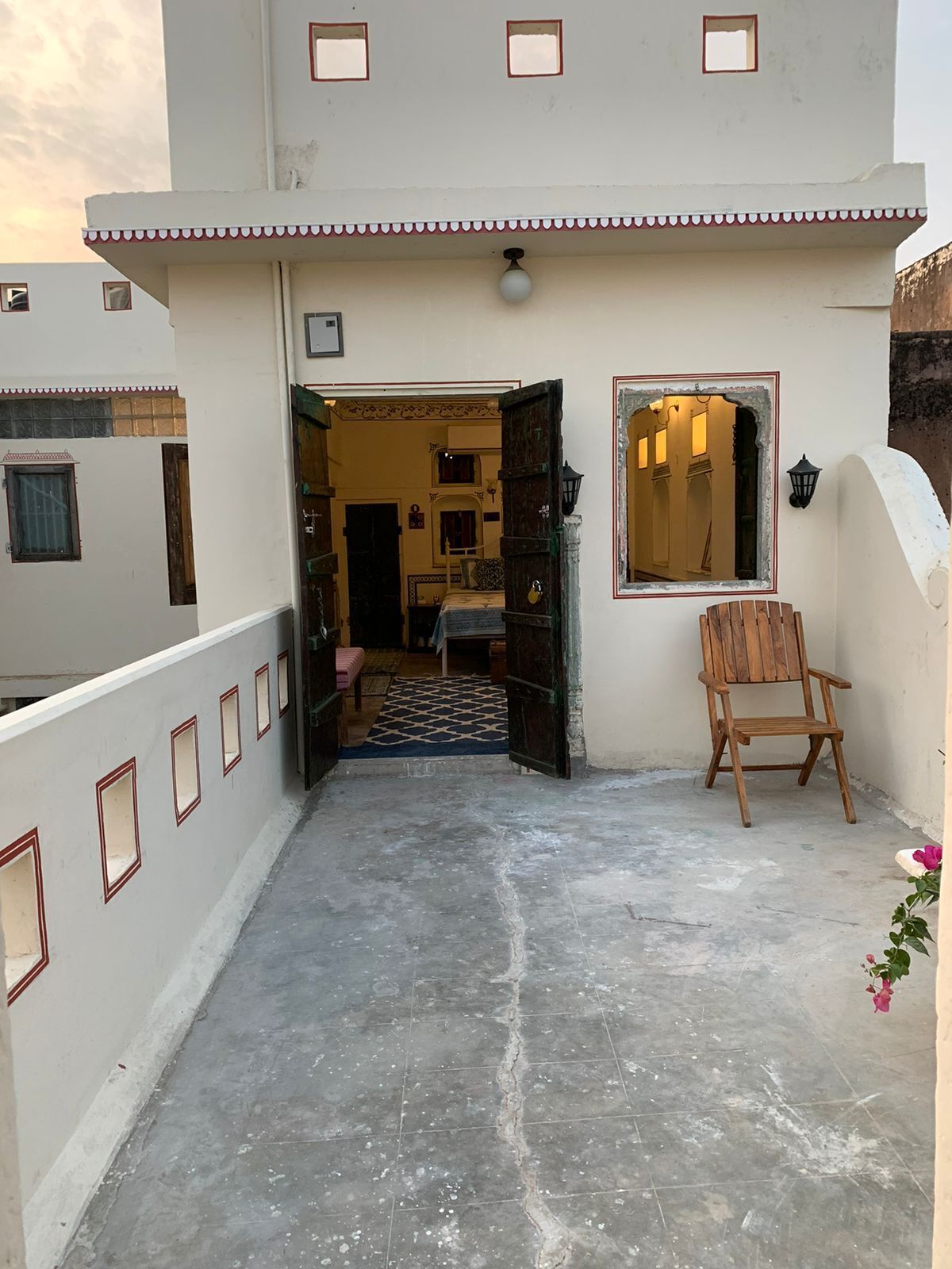A courtyard with a wooden chair, a small table, and a mirror on the wall.