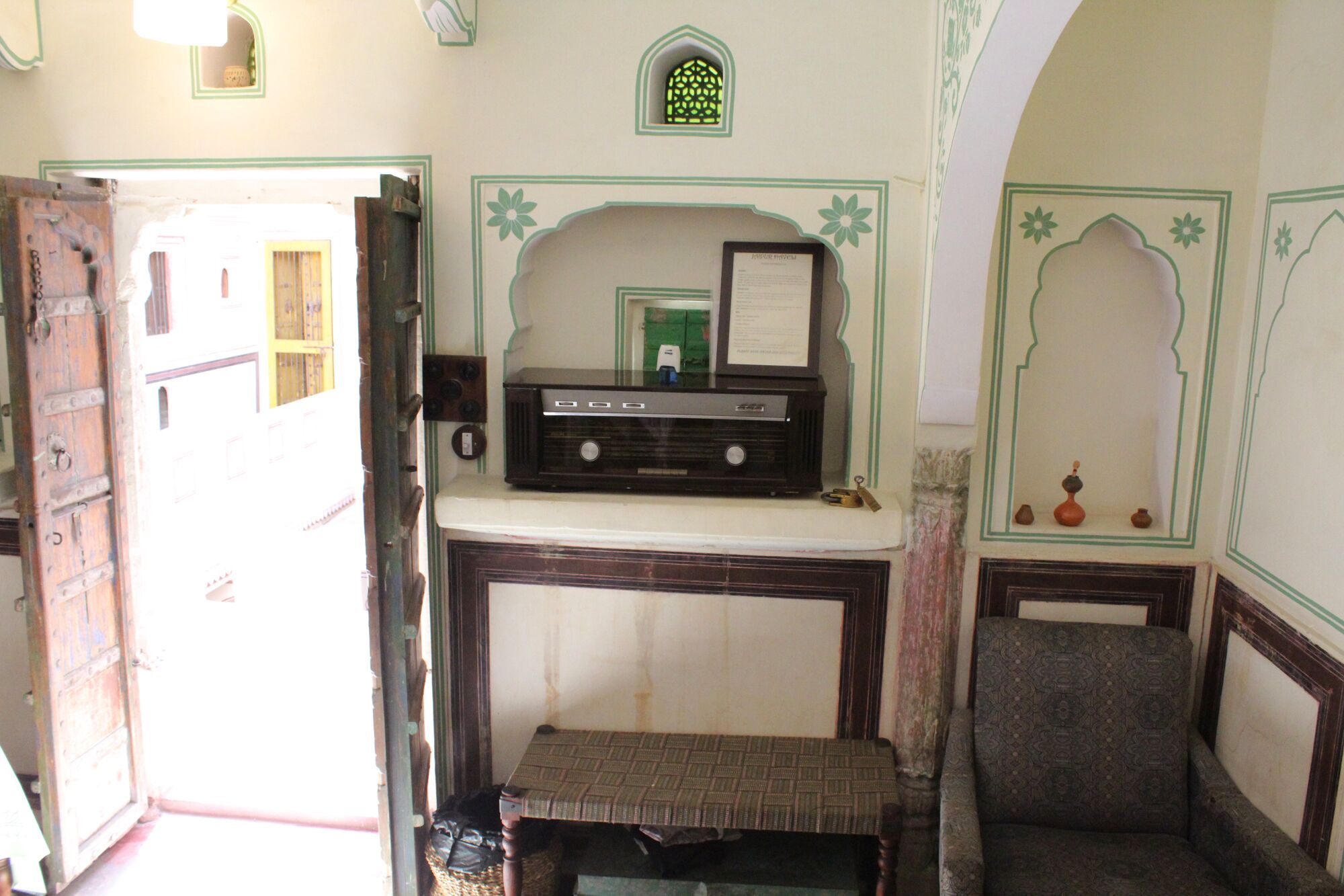A traditional room with a radio on a shelf, a bench, and a small table with a framed certificate.