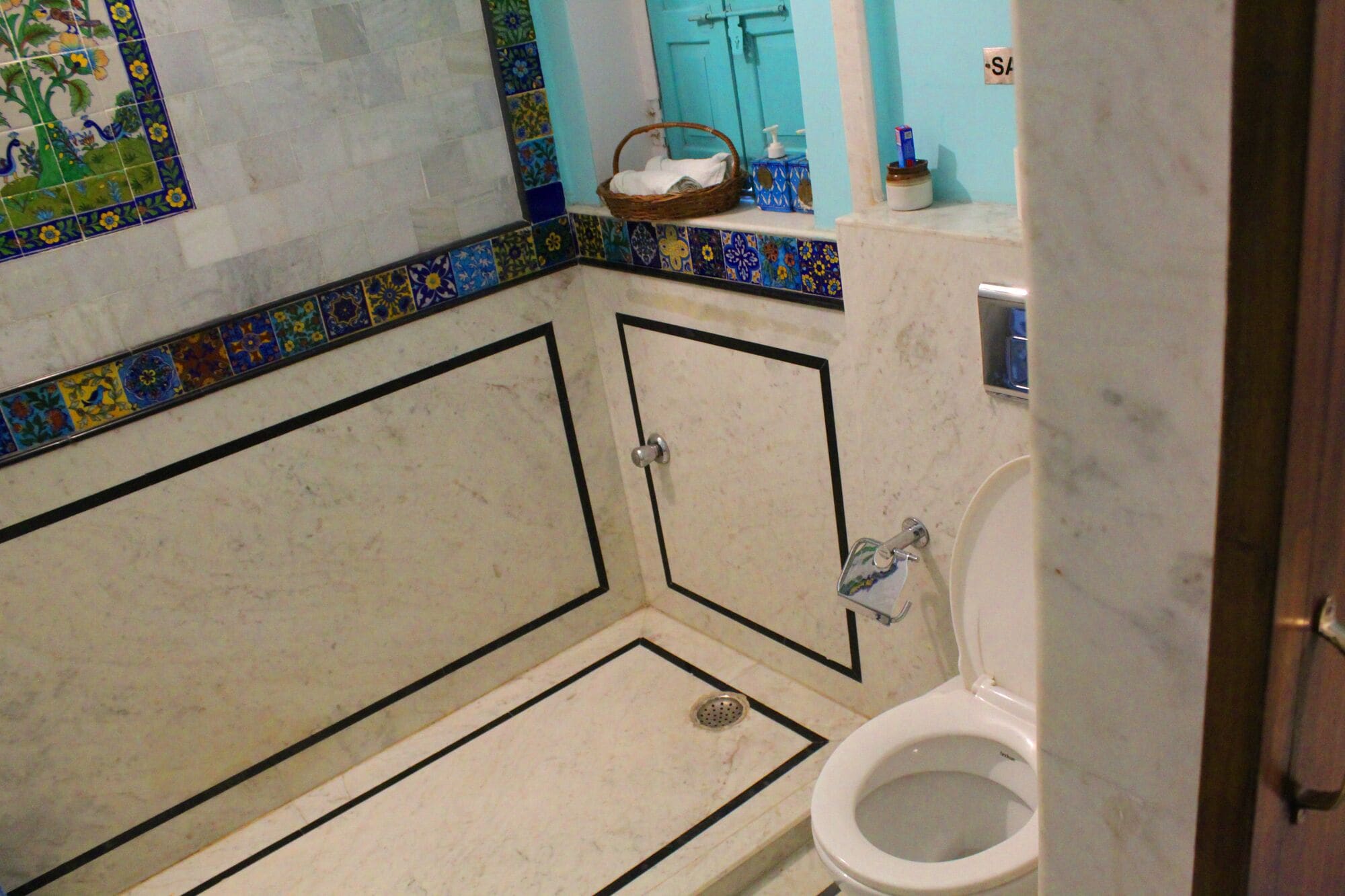 A bathroom with a white toilet, a shower area, and a sink with a soap dispenser.