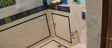 A bathroom with a white toilet, a shower area, and a sink with a soap dispenser.