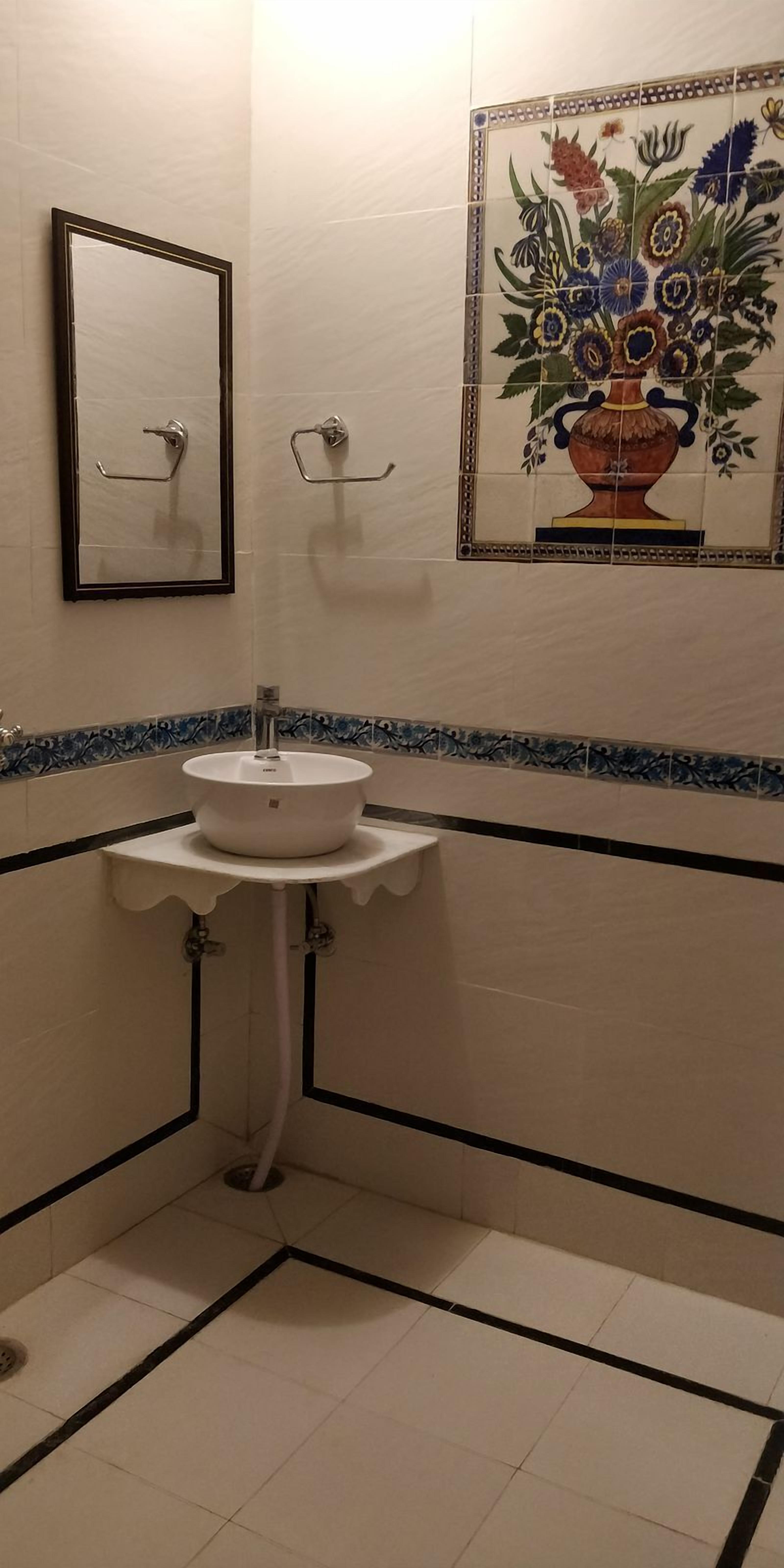 Un baño con lavamanos blanco, un espejo y una pared decorada con azulejos.