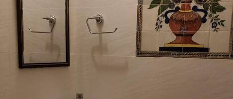 Un baño con lavamanos blanco, un espejo y una pared decorada con azulejos.