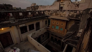 Um pátio com arquitetura tradicional, incluindo um edifício com janelas em arco e varanda.