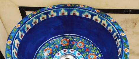 A bathroom sink with a blue basin and floral tile backsplash.
