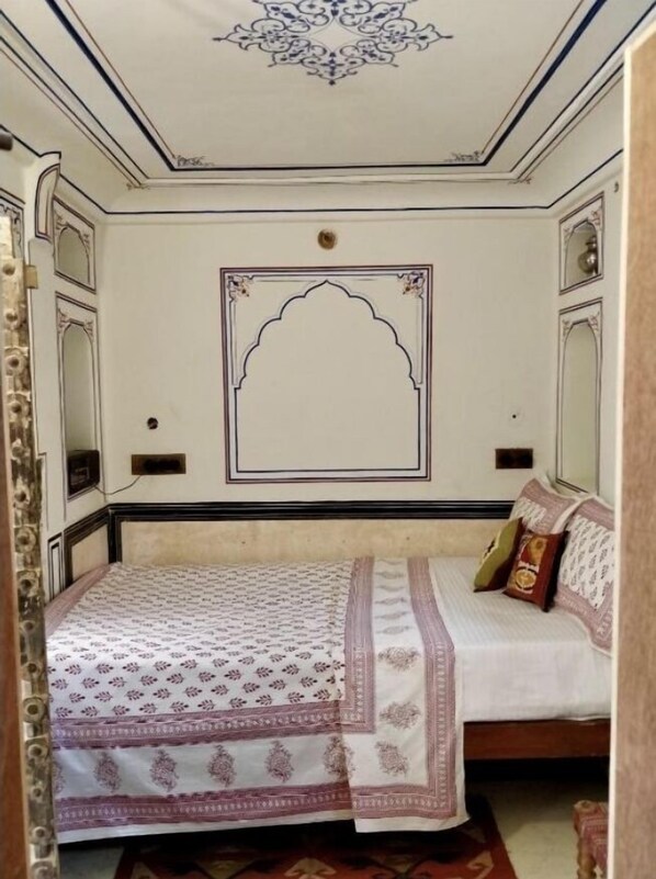 A room with a bed, a decorative ceiling, and a wall with a geometric pattern.