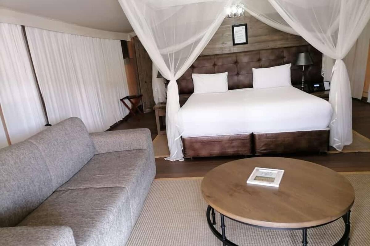 A bedroom with a large bed, a sofa, and a round table.