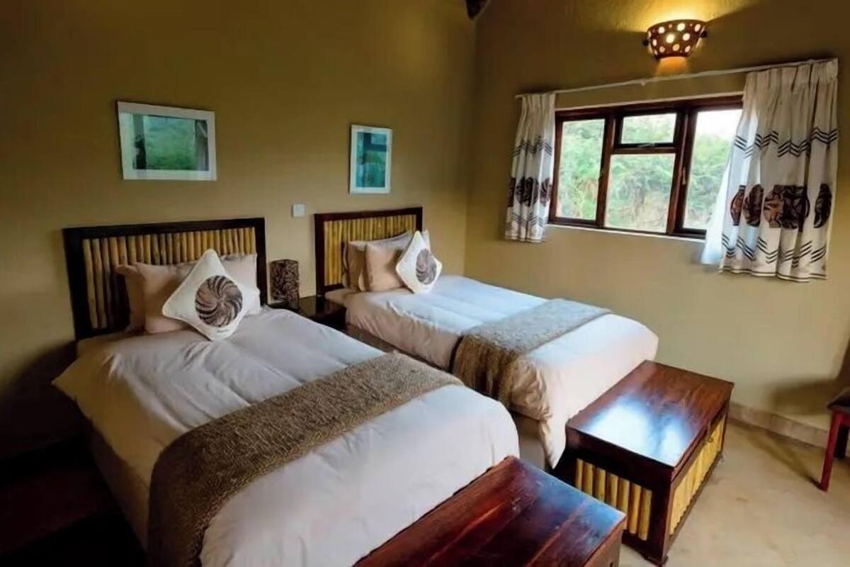 A room with two beds, wooden headboards, and a window with curtains.
