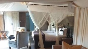 Une chambre à coucher avec un lit à baldaquin, un canapé, une petite table et une chaise.