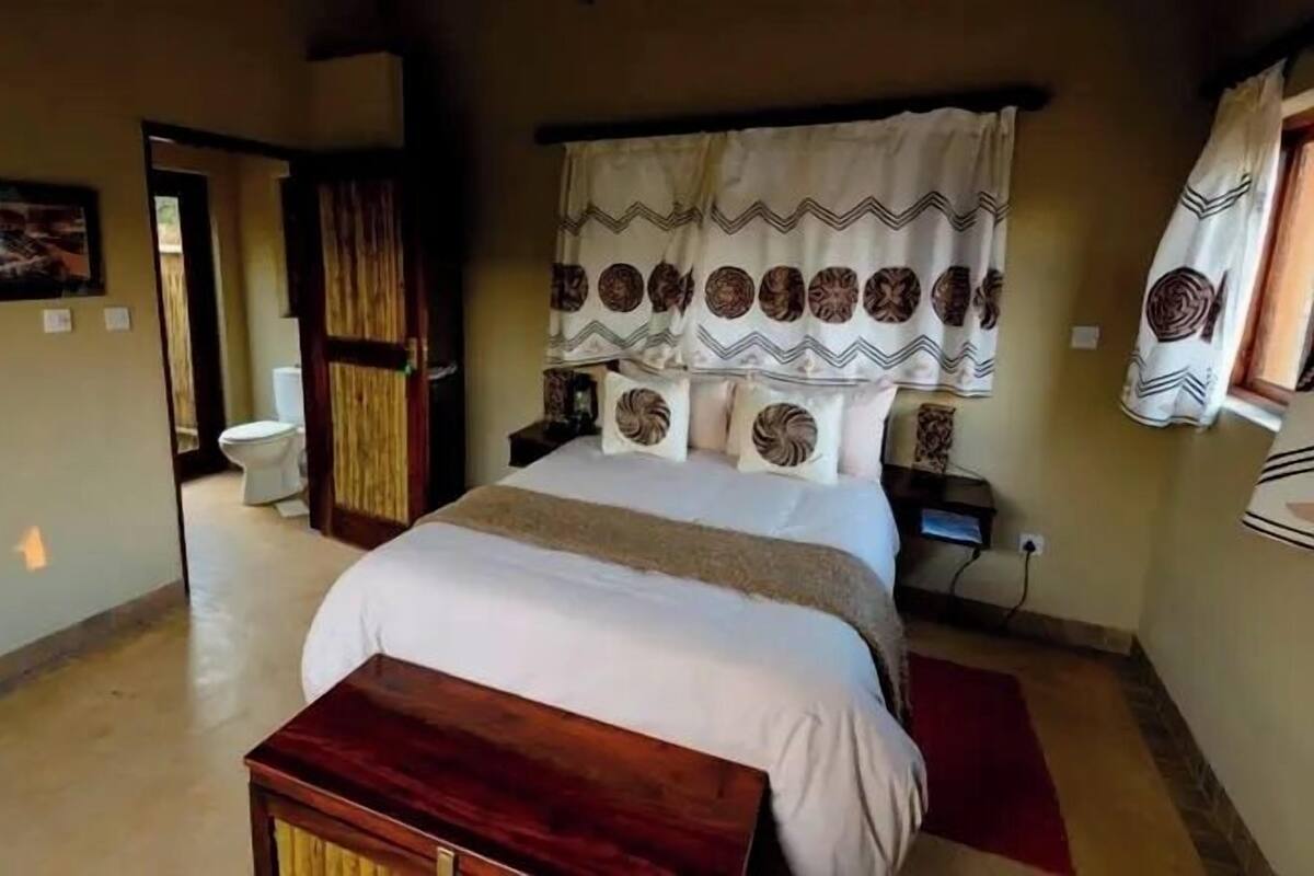 A bedroom with a large bed, a wooden bench, a nightstand, and a bedside table.