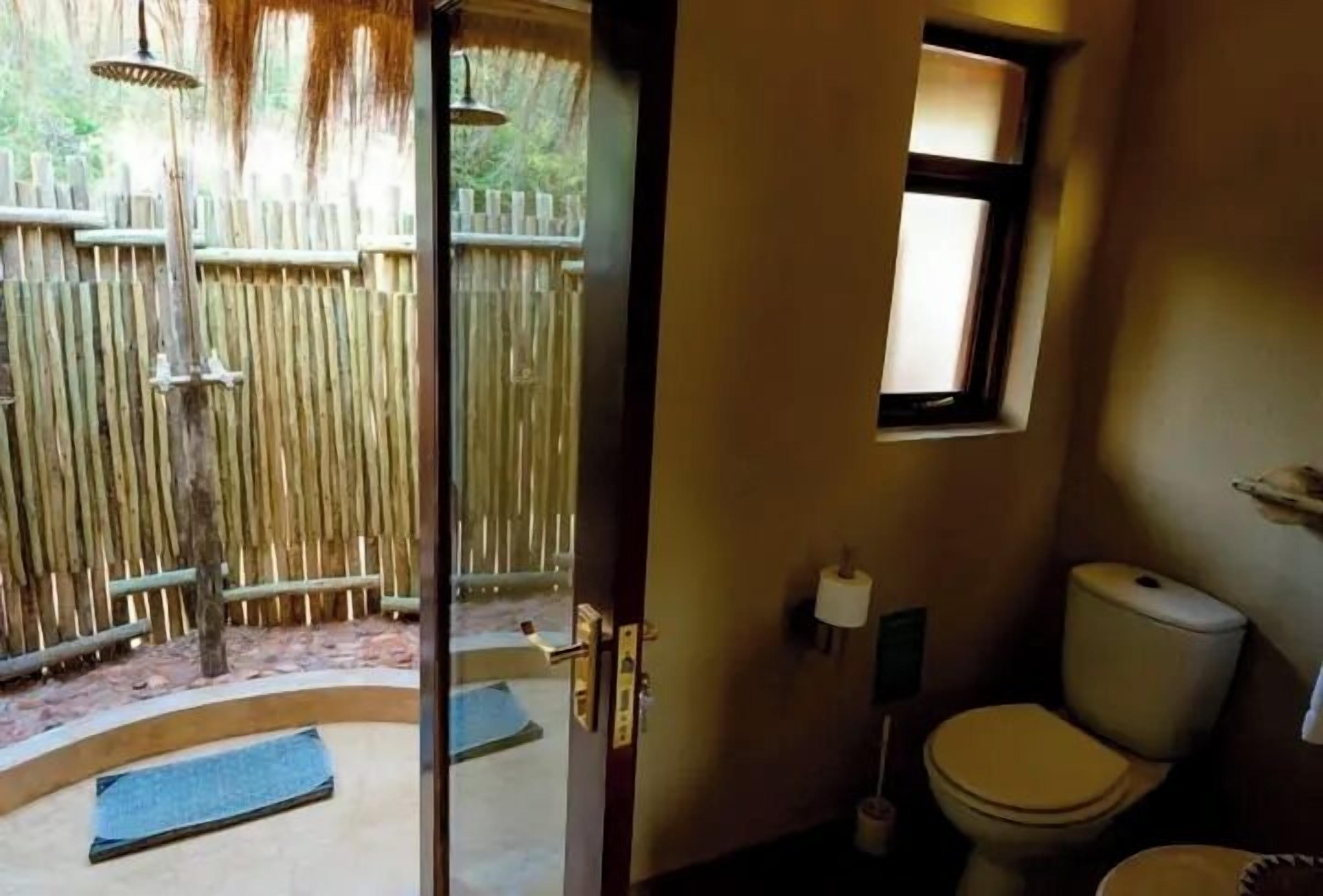 A bathroom with a toilet, a small window, and a wooden fence outside.