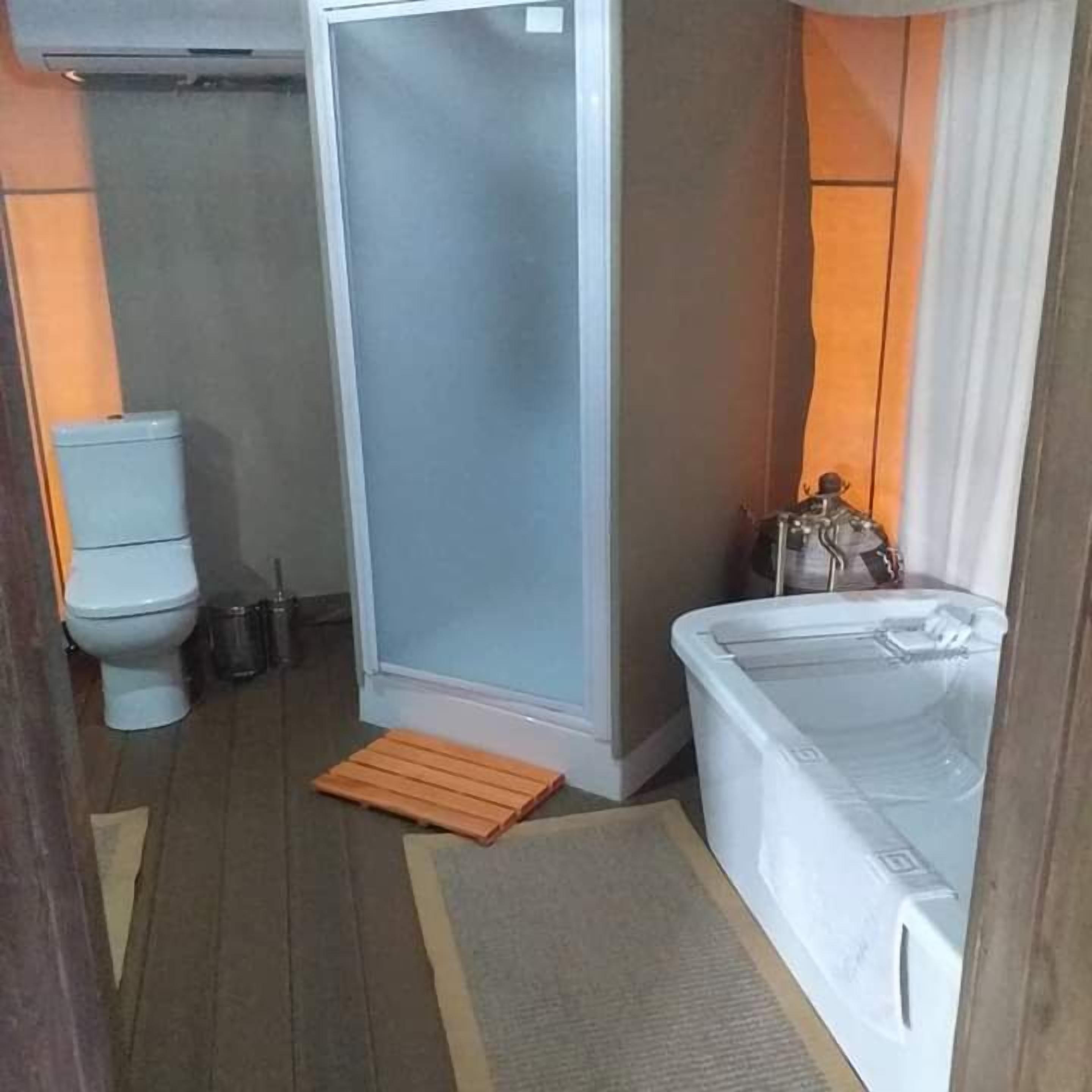 Un baño compacto con inodoro, cabina de ducha y bañera.